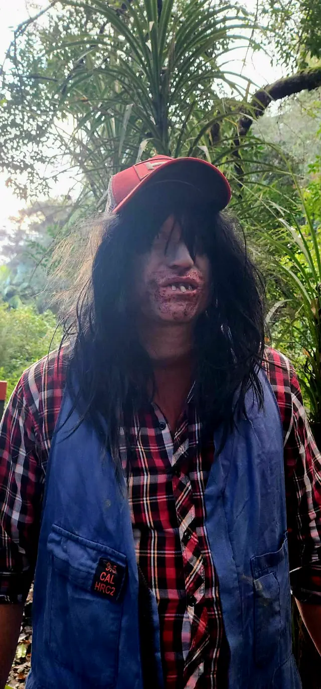 Close-up of the machete character, long black hair hanging over his face under a red cap and blood around his bared teeth