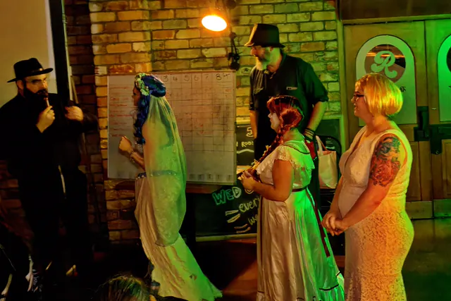 Costume judging at a Northland Horror quiz night - a bride in a torn veil, a doll in a lace dress and two others line up in front of a scoreboard while the host looks on
