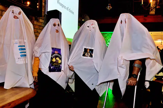 Four guests under white bedsheet ghost costumes with eye holes cut out, each pinned with a clue for the quiz round