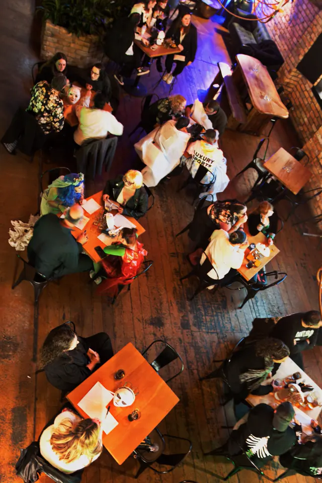 Looking down on a full room of quiz night tables from the mezzanine, costumed teams huddled over their answer sheets
