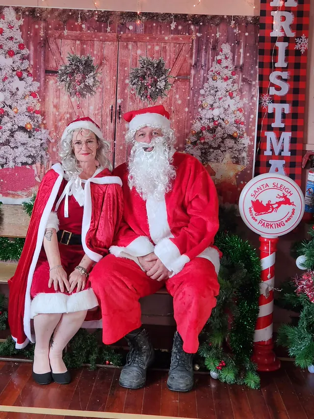 Two of the crew as Santa and Mrs Claus seated in a Christmas grotto they built for photographs