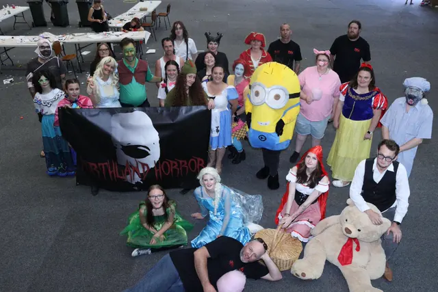 The Northland Horror volunteer crew of about twenty-five people in costume gathered around their black banner in McKay Stadium, ranging from Snow White and a Minion to zombies and ghouls